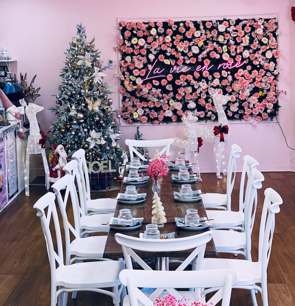 A long table set for a group under the flower wall and the La vie en rose neon sign