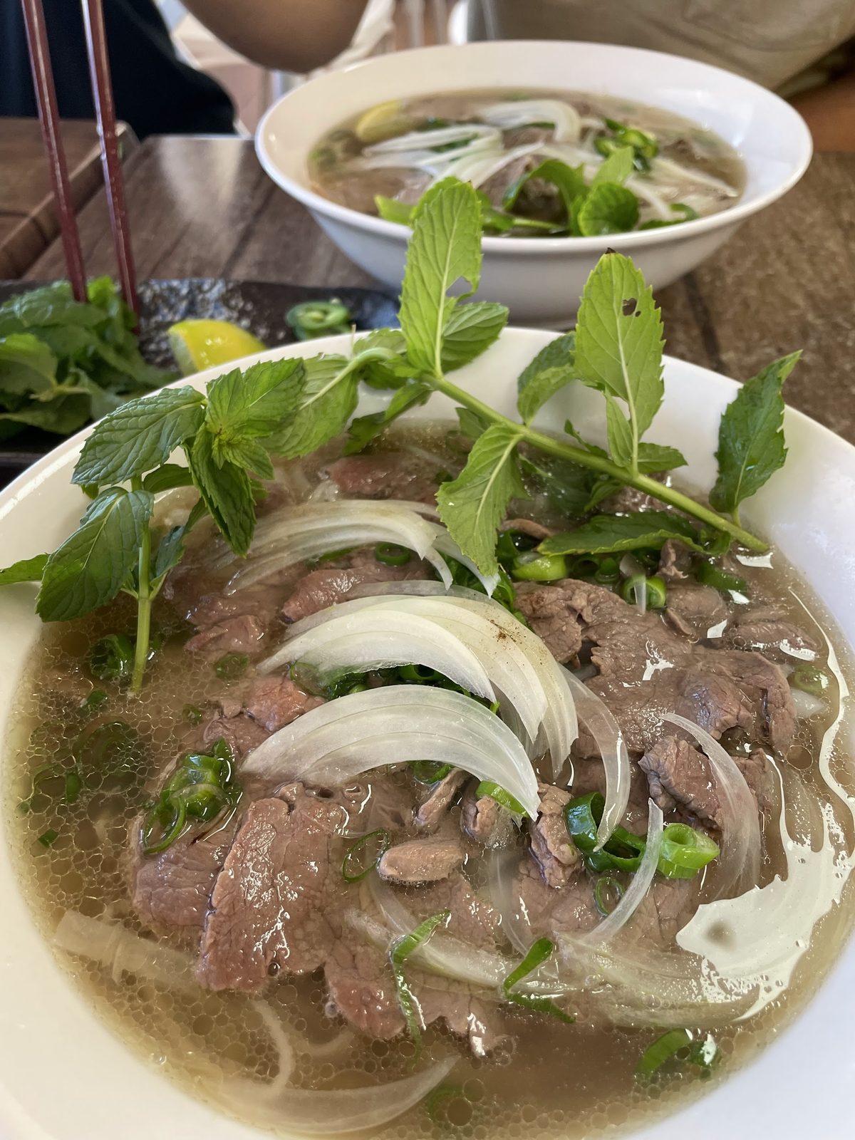 Beef pho topped with mint and sliced onion